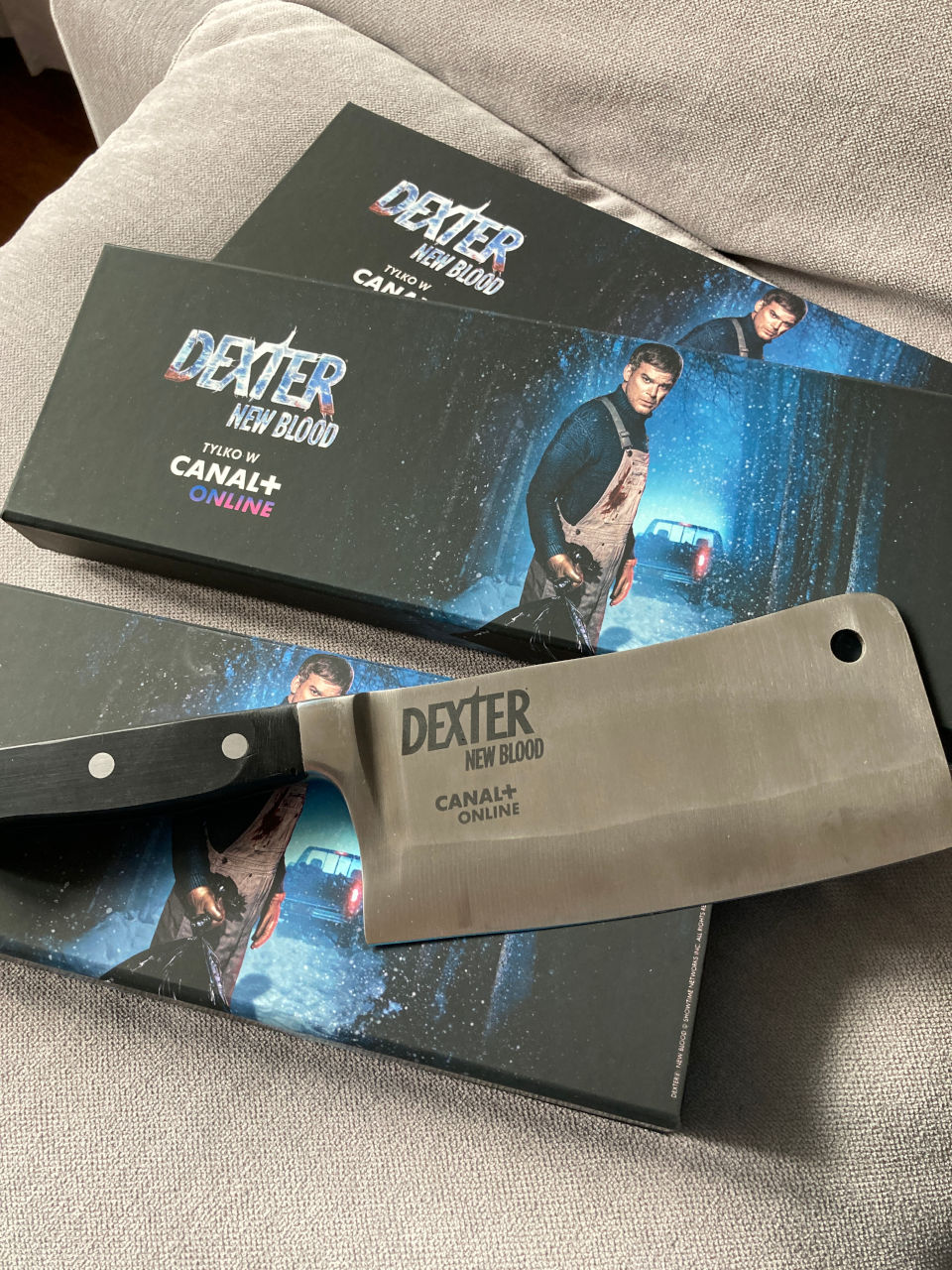 Zestaw gadżetów Canal+ Dexter New Blood przygotowany przez Deuter DLM – podłużne czarno-niebieskie opakowanie z grafiką Dextera, ulotką i tasakiem w środku